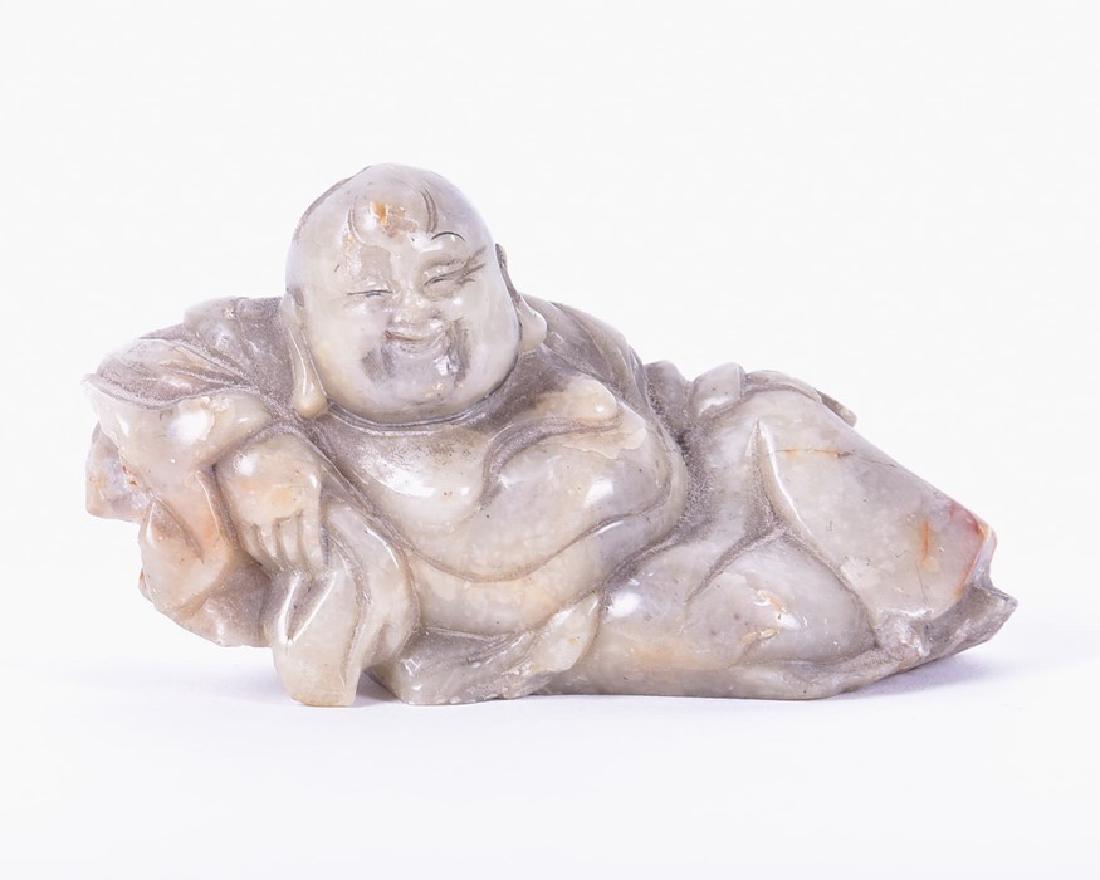 A Chinese carved jade Buddha modelled in a: A Chinese carved jade Buddha modelled in a reclining position with a flowing robe, 9 cm x 5 cm.