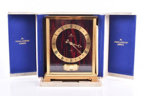 A Jaeger Le Coultre 'Embassy Red' Atmos clock circa: A Jaeger Le Coultre 'Embassy Red' Atmos clock circa 1972, the brass case with red faux marble front and side panels, the base with start/stop lever, the brass chapter ring with Roman numerals. Clock 2