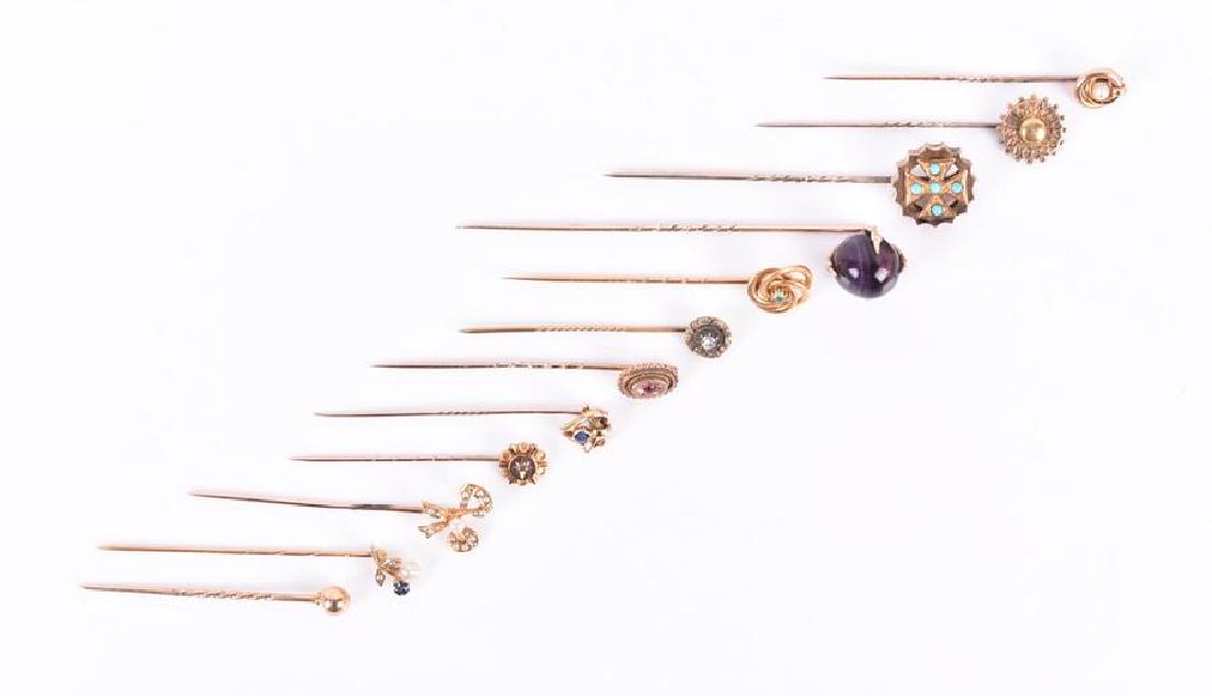 A group of various stick pins to include a yellow: A group of various stick pins to include a yellow metal and amethyst claw pin, a turquoise cross pin, a pearl-set ribbon-style pin, an emerald and gold cluster pin, two pearl pins, a sapphire knot pin