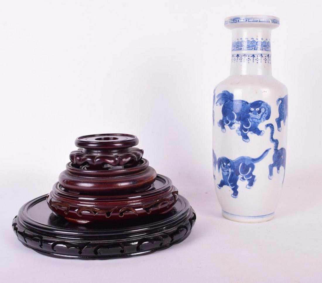 A 19th century or earlier Chinese vase of rouleau: A 19th century or earlier Chinese vase of rouleau form, decorated with a menagerie of guardians in blue underglaze (restored), along with four Chinese hardwood stands, 29 cm high.