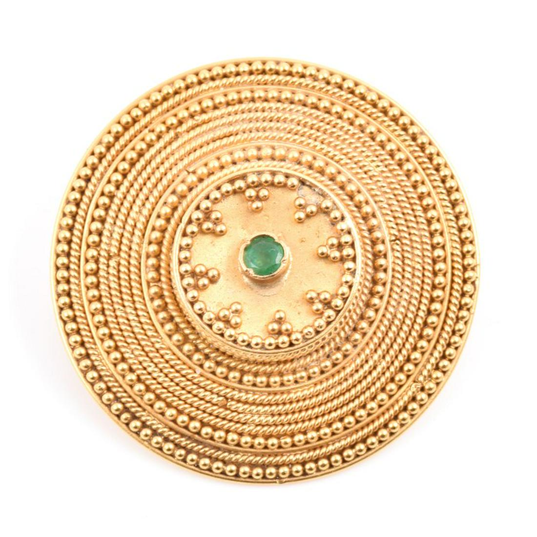 A yellow metal and emerald brooch of rounded form, in: A yellow metal and emerald brooch of rounded form, in the Etruscan Revival style, with applied beaded decoration, centred with a small emerald, 3.2 cm diameter.