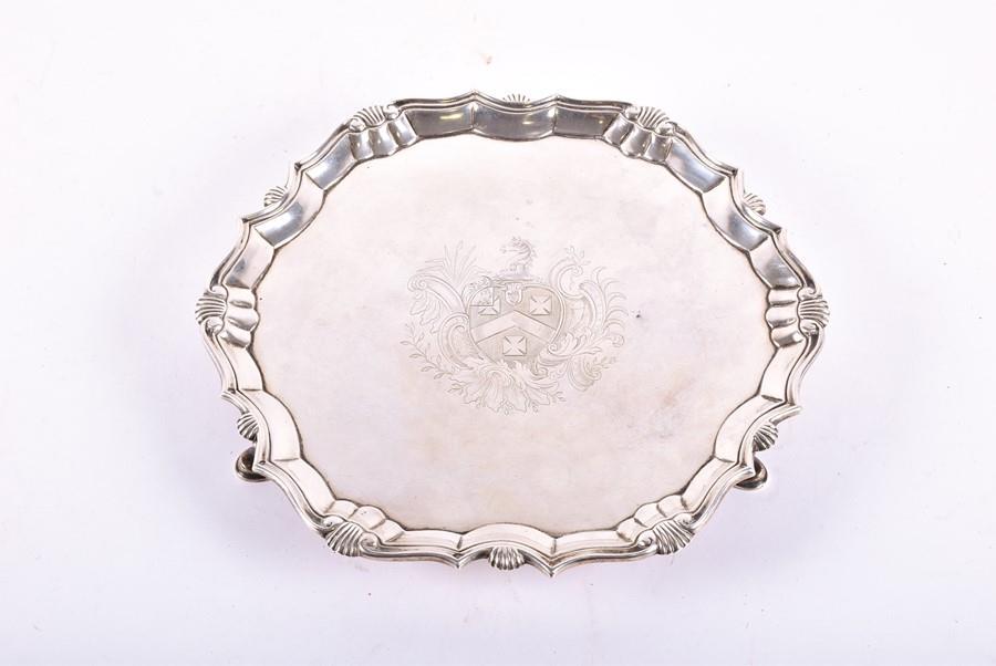 A George II silver salver London 1738, by Robert: A George II silver salver London 1738, by Robert Abercromby, the shaped border decorated with shell motifs, an armorial crest to the centre, on three feet, 24 cm diameter, 18 ozt.
