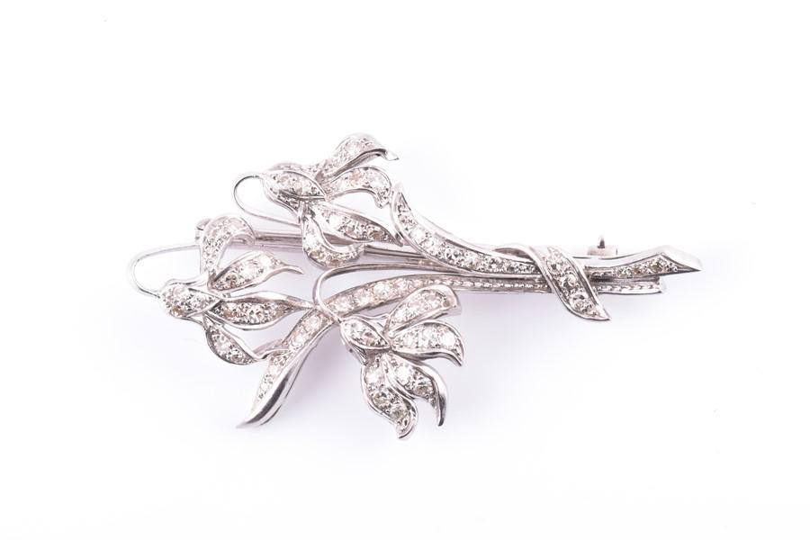 A white metal and diamond brooch of floral form, set: A white metal and diamond brooch of floral form, set with round-cut diamonds, stamped 56, 9.3 grams.