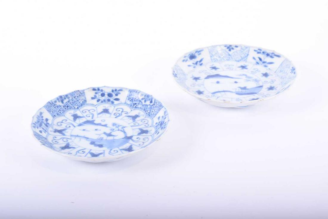 A pair of Chinese blue and white Cau Mau shipwreck: A pair of Chinese blue and white Cau Mau shipwreck saucers, Yongzheng, with landscape centre framed by panels of moths, peony and hatching, applied Sotheby's - Unicom label to the underside, 12cm diam
