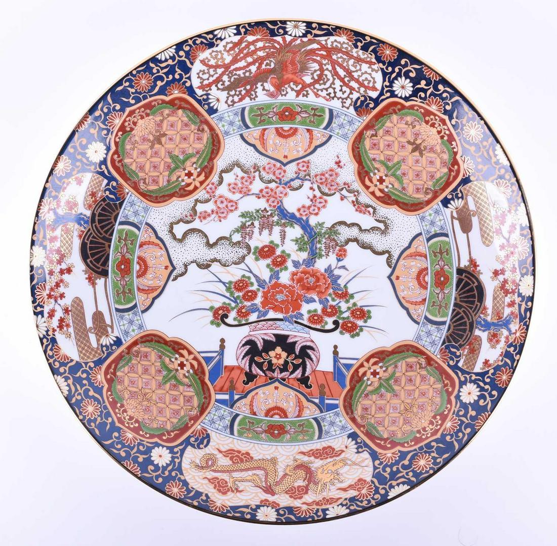 A large 20th century Arita ware porcelain charger,: A large 20th century Arita ware porcelain charger, profusely decoarated in polychrome enamels with bonsai beneath clouds, the border with dragons and repeating geometric reserves, character marks vers