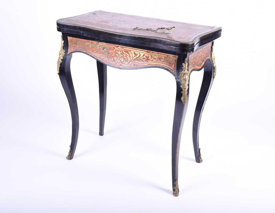 A late 19th century boulle marquetry card table, with: A late 19th century boulle marquetry card table, with gilt metal mounts and red tortoiseshell colour, the serpentine hinged swivel top decorated with stylised foliage, opening to reveal a green baize 