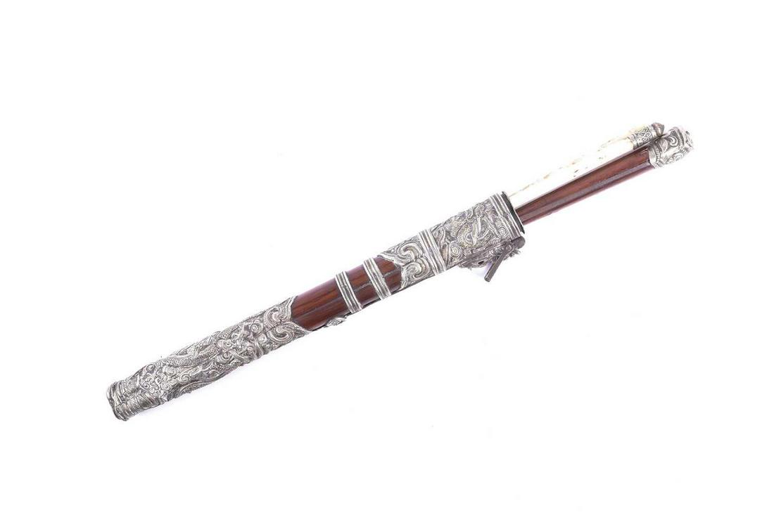 A Chinese knife and chopstick set, the case with: A Chinese knife and chopstick set, the case with embossed white metal mounts decorated with dragons amongst scrolling clouds, a bat, ruyi heads and peony, the suspension loop attached to a cast dragon