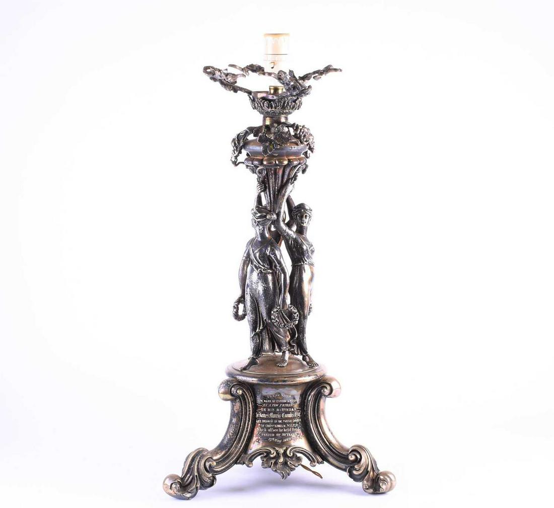 An Victorian silver plated figural lamp of imposing: An Victorian silver plated figural lamp of imposing proportions, with grape and vine decoration over three Classical maidens, on a rococo style tri-form base, 62 cm high to include lampholder.