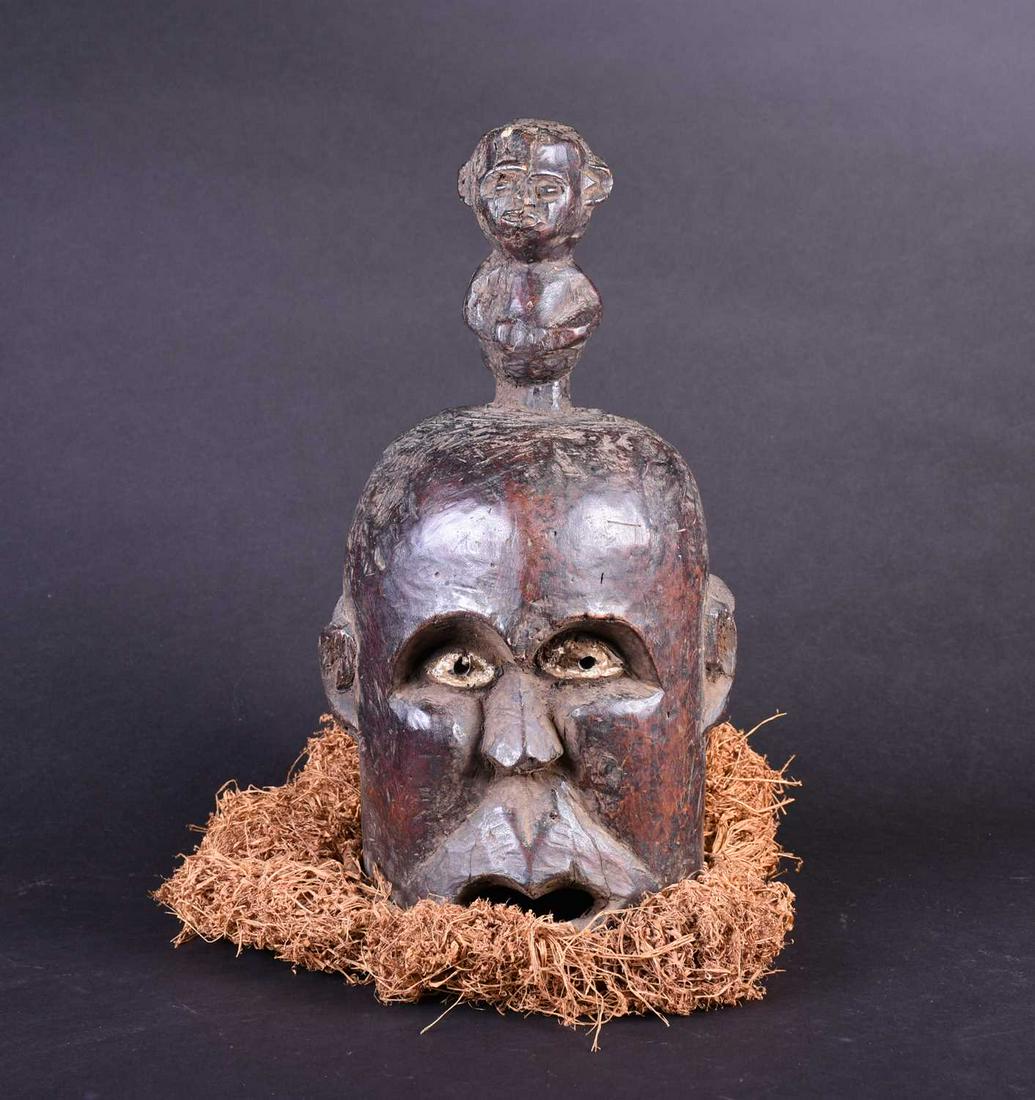 A Bamum Janus mask, Cameroon, with kaolin heightened: A Bamum Janus mask, Cameroon, with kaolin heightened eyes, surmounted by a Janus figure, with dried grass beard, 45cm Footnote: The collection of the late Reverend Alan Dupuy