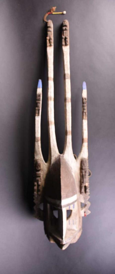 A Dogon mask, Mali, with two tall central prongs: A Dogon mask, Mali, with two tall central prongs flanked by smaller prongs, each with relief carved male and female figural pilasters, painted in blue, white and brown pigment, one tall prong with yel