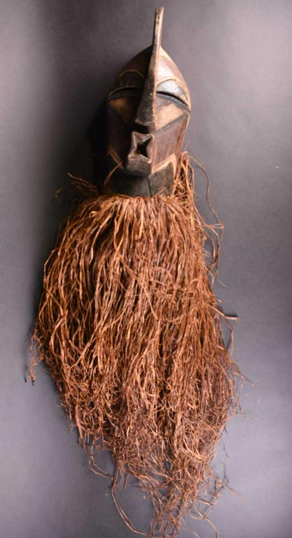 A Kifwebe mask, Songye, Democratic Republic of Congo,: A Kifwebe mask, Songye, Democratic Republic of Congo, the blank comb above a geometric carved head and face, coloured in red, white and black, with long grass beard, the mask 43cm Footnote: Formerly i