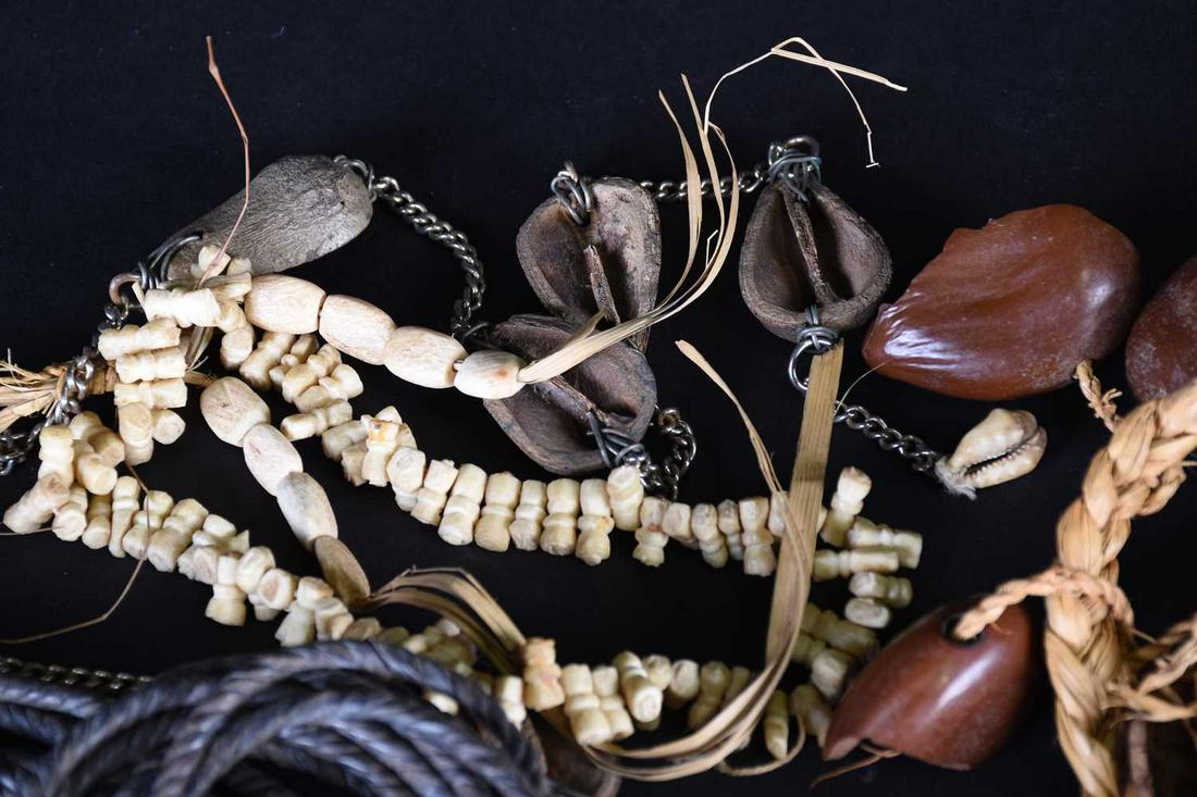 African jewellery, comprising four seed pod necklaces,: African jewellery, comprising four seed pod necklaces, a carved bone necklace, three combs and a nine strand rope twist leather short noose form whip?