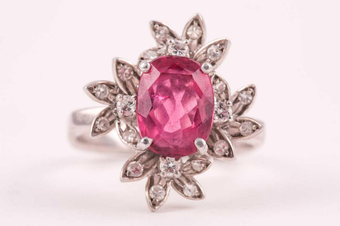 A diamond and pink tourmaline cocktail ring, set with a: A diamond and pink tourmaline cocktail ring, set with a mixed oval-cut tourmaline of approximately 4.0 carats, within stylised floral mount inset with small diamonds, the shaped shank unmarked (tests 