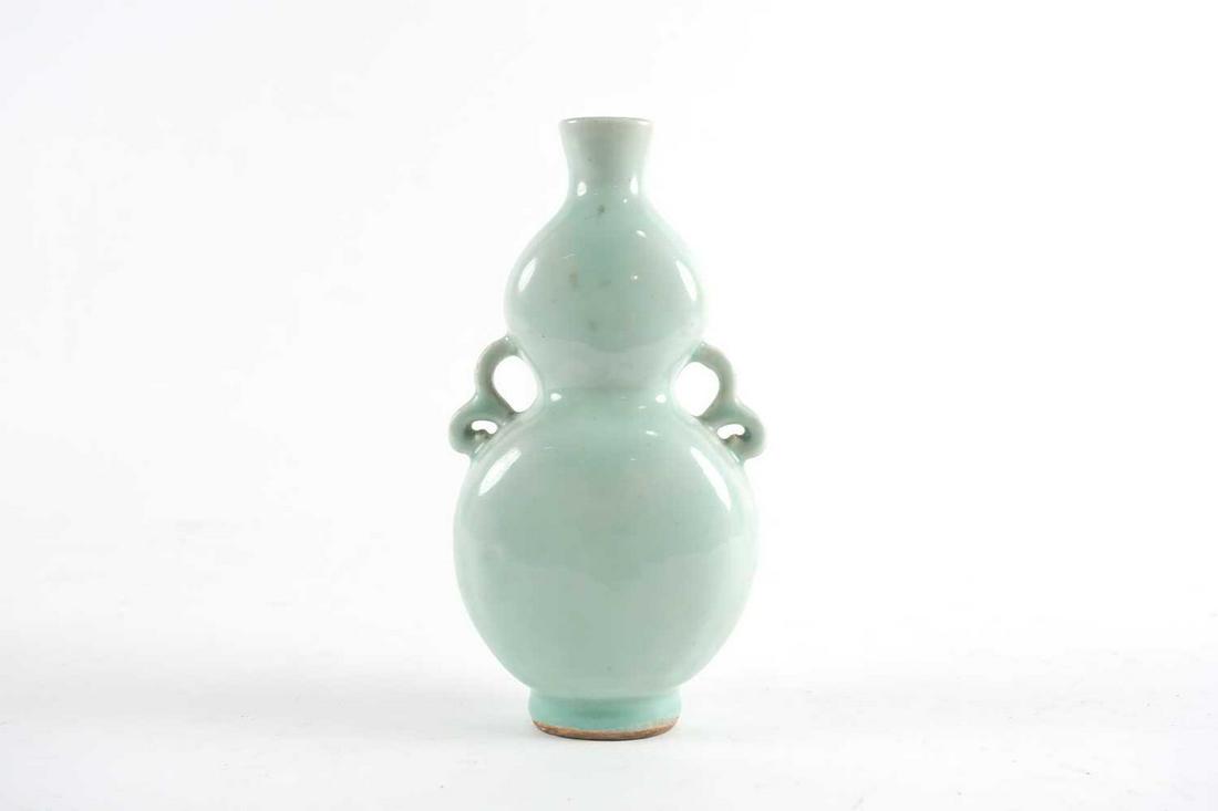 A Chinese celadon gourd vase, Qing, 18th/19th century,: A Chinese celadon gourd vase, Qing, 18th/19th century, of flattened form with pierced loop handles, 20cm high Footnote: From the A.F. Bohman collection.