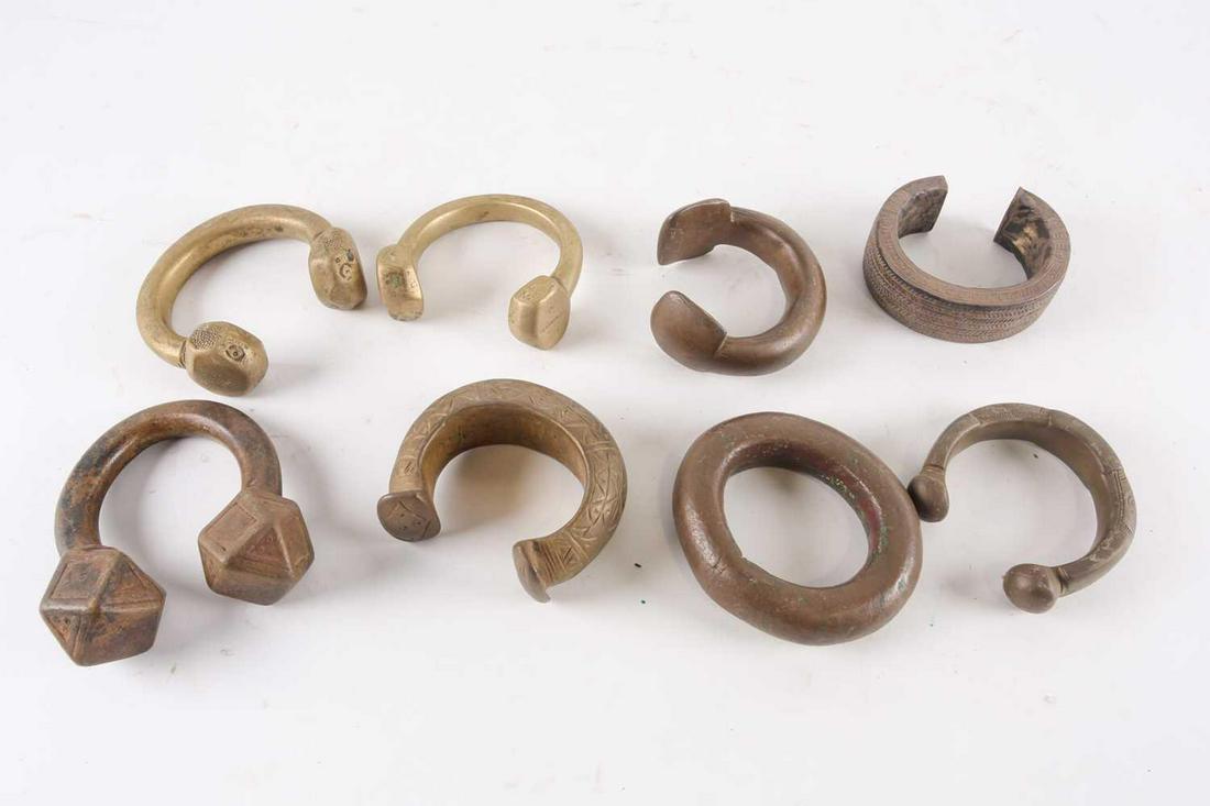 Seven African bronze and brass Manillas, 19th century: Seven African bronze and brass Manillas, 19th century and later, and a silver coloured metal bangle