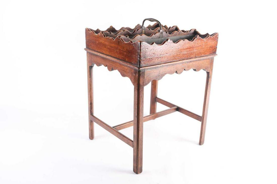 A George III mahogany butler's three-section wine: A George III mahogany butler's three-section wine carrier, with a shaped edge and brass handle and zinc lining, supported on a later mahogany stand, 39 cm long x 35 cm wide x 55 cm high.