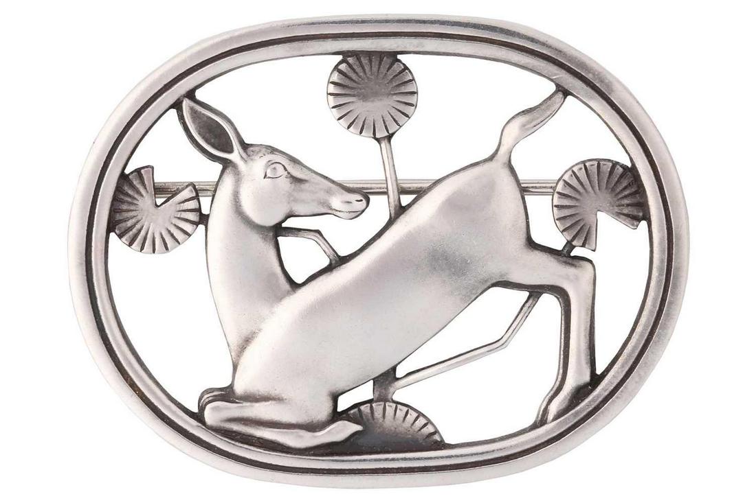 Georg Jensen - A brooch depicting kneeling fawn and flowers, fitted with hinged pin stem and: Georg Jensen - A brooch depicting kneeling fawn and flowers, fitted with hinged pin stem and roll-over safety catch, designed by Arno Malinowski, No. 256, 1933-44 maker's mark, stamped as 925S, overal