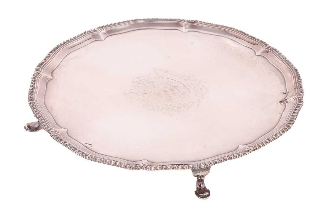 A George III silver salver, by Richard Carter, Daniel Smith & Robert Sharp, London 1799, of circular: A George III silver salver, by Richard Carter, Daniel Smith & Robert Sharp, London 1799, of circular form with scalloped and gadrooned rim, on hoof feet, engraved with a crest with ribbon and floral m
