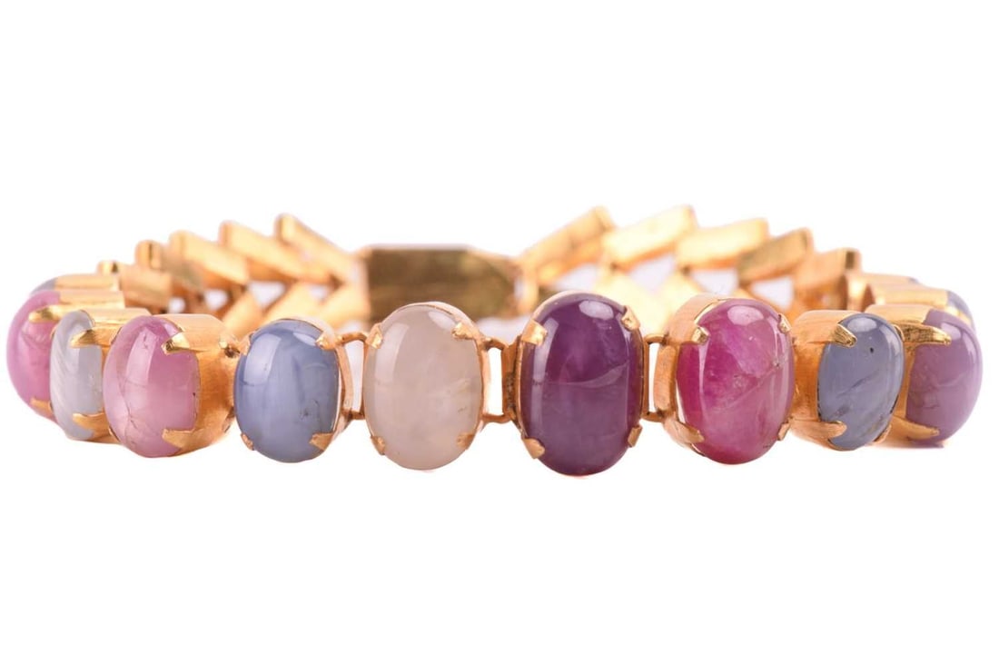 A star corundum bracelet, articulated links claw-set with thirteen-star corundum cabochons in: A star corundum bracelet, articulated links claw-set with thirteen-star corundum cabochons in graduated sizes, showing six-ray asterism on rubies and sapphires, attached to sections of chevron links a