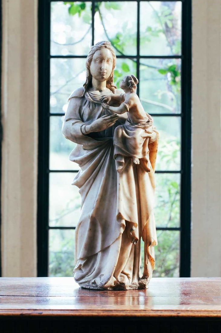 A 16th/17th-century alabaster carving of the Madonna and Child (Mary lacking a crown), depicted: A 16th/17th-century alabaster carving of the Madonna and Child (Mary lacking a crown), depicted wearing a long draped robe with the Infant Jesus in her arms, dressed in tunic and wrapped in a shawl, 5
