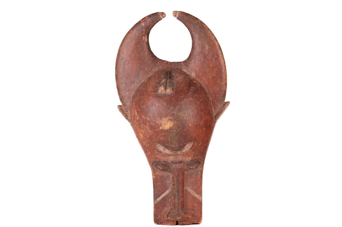 A Baule people wooden helmet animal mask (Bo Nun Amuin) with curved horns and signs of polychromic: A Baule people wooden helmet animal mask (Bo Nun Amuin) with curved horns and signs of polychromic painting, 30 cm wide x 52 cm