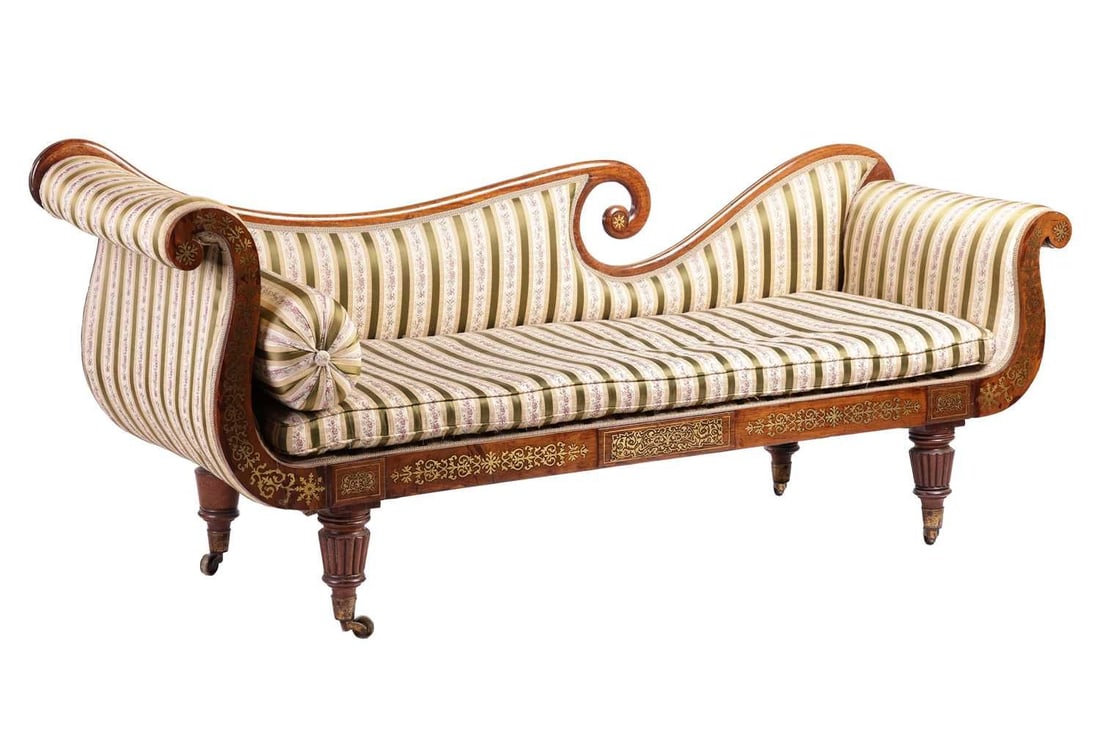In the manner of John McLean a Regency brass inlaid rosewood double scroll chaise longue, with spent: In the manner of John McLean a Regency brass inlaid rosewood double scroll chaise longue, with spent back rail, striped sateen upholstery and horsehair squab and bolster en suite, supported by four sh