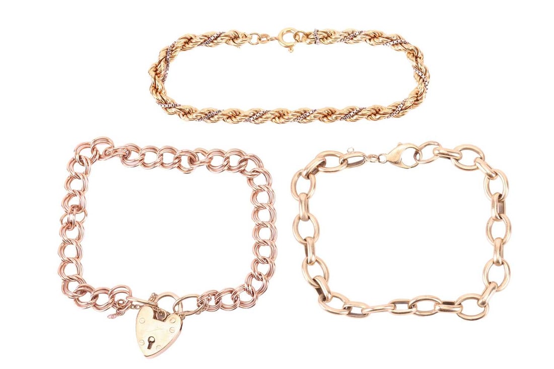 Three chain bracelets; the first comprising a series of 9ct rose gold double curb links, completed w: Three chain bracelets; the first comprising a series of 9ct rose gold double curb links, completed with a 9ct yellow gold heart-shaped padlock clasp, Birmingham assay marks, 20.0 cm long; a cable link