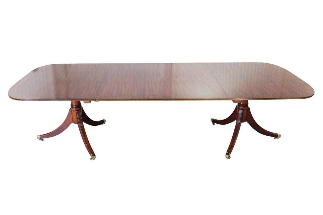 A craftsman-made George III-style crossbanded mahogany twin pedestal dining table, 20th century,: A craftsman-made George III-style crossbanded mahogany twin pedestal dining table, 20th century, possibly by Brights of Nettlebed, with "D" shaped ends and two leaf inserts, supported by a pair of ped