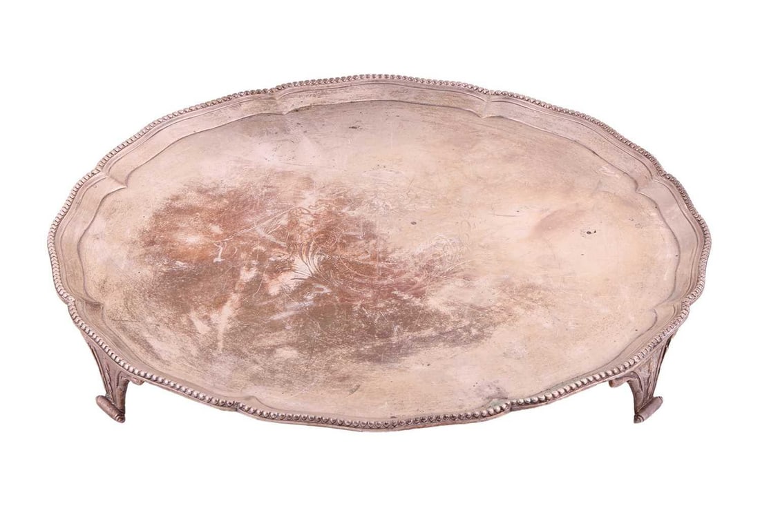 A George III silver salver, with a shaped beaded border, engraved with a coat of arms, on three feet: A George III silver salver, with a shaped beaded border, engraved with a coat of arms, on three feet with scroll terminals, the reverse engraved with a staghead creat, by Robert Jones and John Scofiel