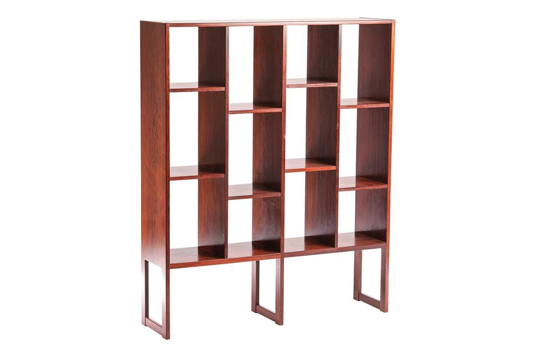 A 1970s Svend Langkilde rosewood bookstand, of plain design with stepped shelf compartments, on: A 1970s Svend Langkilde rosewood bookstand, of plain design with stepped shelf compartments, on rectangular legs with floor height stretchers, stamped 'Langklide', 116 cm wide, 30 cm deep, 140 cm high