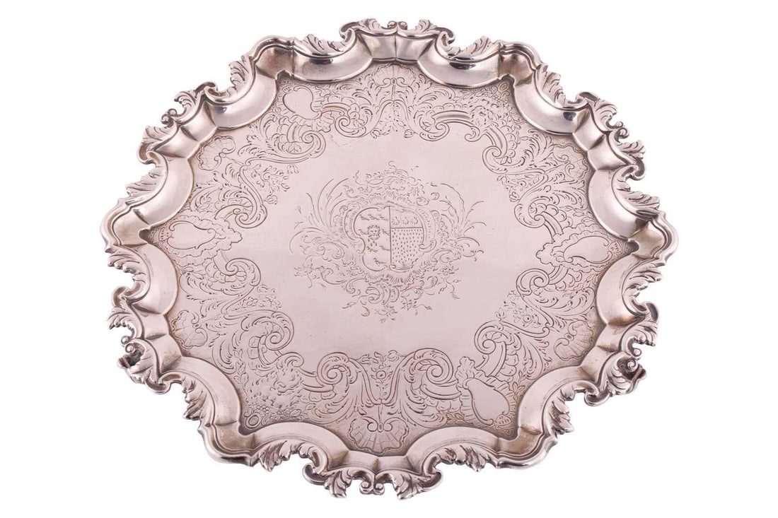 A George II Irish silver salver by Robert Calderwood, Dublin circa 1740, of circular form with cast: A George II Irish silver salver by Robert Calderwood, Dublin circa 1740, of circular form with cast foliate border, the centre engraved with a coat of arms with a flat chased border of shells, masks a