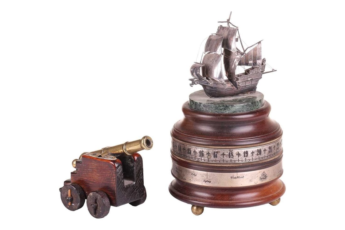 A 19th-century miniature naval cannon with a tapering girdled body on a stepped oak carriage with: A 19th-century miniature naval cannon with a tapering girdled body on a stepped oak carriage with pegged wooden wheels, 16 cm long, together with a Charles Frodsham of London, "The St.James's House Co
