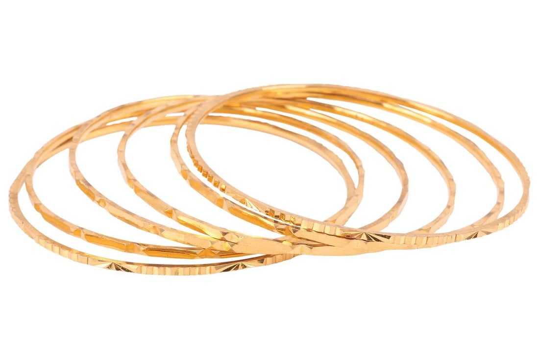 A set of six Indian closed bangles of faceted geometric design, in unmarked yellow metal testing as (1 of 3)