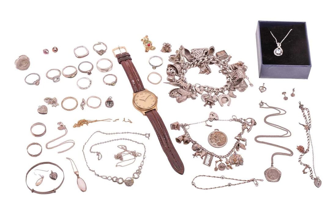 A group lot of silver and costume jewellery; to include three silver charm bracelets, various religi: A group lot of silver and costume jewellery; to include three silver charm bracelets, various religious medals, silver and white metal chains, gem-set rings, a Lorea wristwatch and other items.