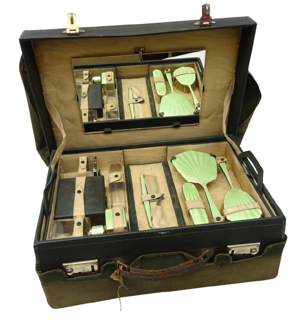 1940's green leather travelling vanity case, the satin: 1940's green leather travelling vanity case, the satin lined interior housing a pull-out folding tray containing a four piece enamel dressing table set, clear glass jars, leather jewellery box and oth