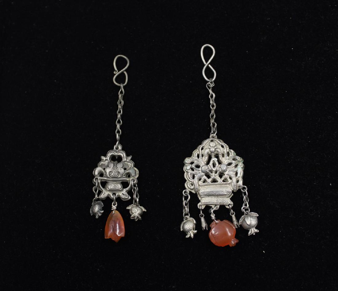 (2) Chinese Silver Lotus Pendants: Two Chinese Silver Lotus Pendants with carved carnelian beads and silver peach tassels. Left pendent measures: 1" x 2" with a total length of 4.5"
