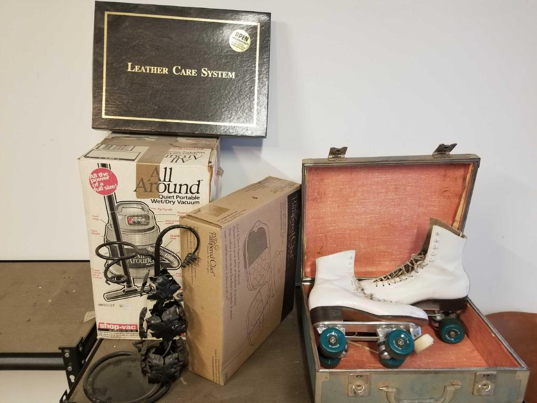 Lot of miscellaneous goods: To include a vintage cased pair of roller skates, a new pampered chef cool and serve square that, a new boxed leather care set, an older 6.0 HP shop vac in box, and a metal display rack.