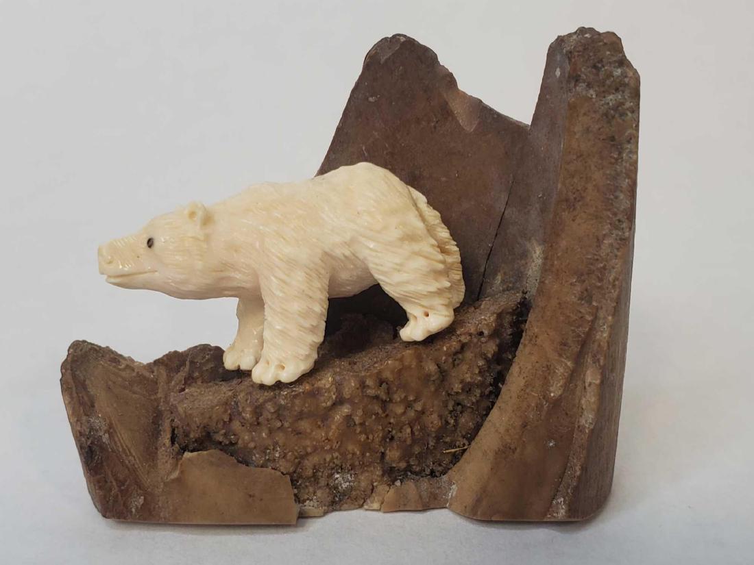 Eskimo carved polar bear on fossilized walrus tusk base: The detailed polar bear resting upon a nice end section of fossilized walrus ivory tusk. Feet have been reglued. Measures approximately 2.25" x 1" x 2".