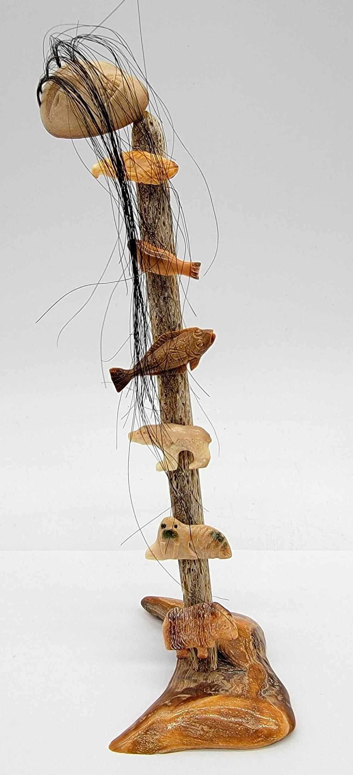 King Island Walrus Tusk & Whalebone Carving #1: A totemic carving topped by a human face with baleen hair and adorned with half a dozen small carvings of Inuit game animals and an Eagle. Remains in excellent condition with no readily apparent maker