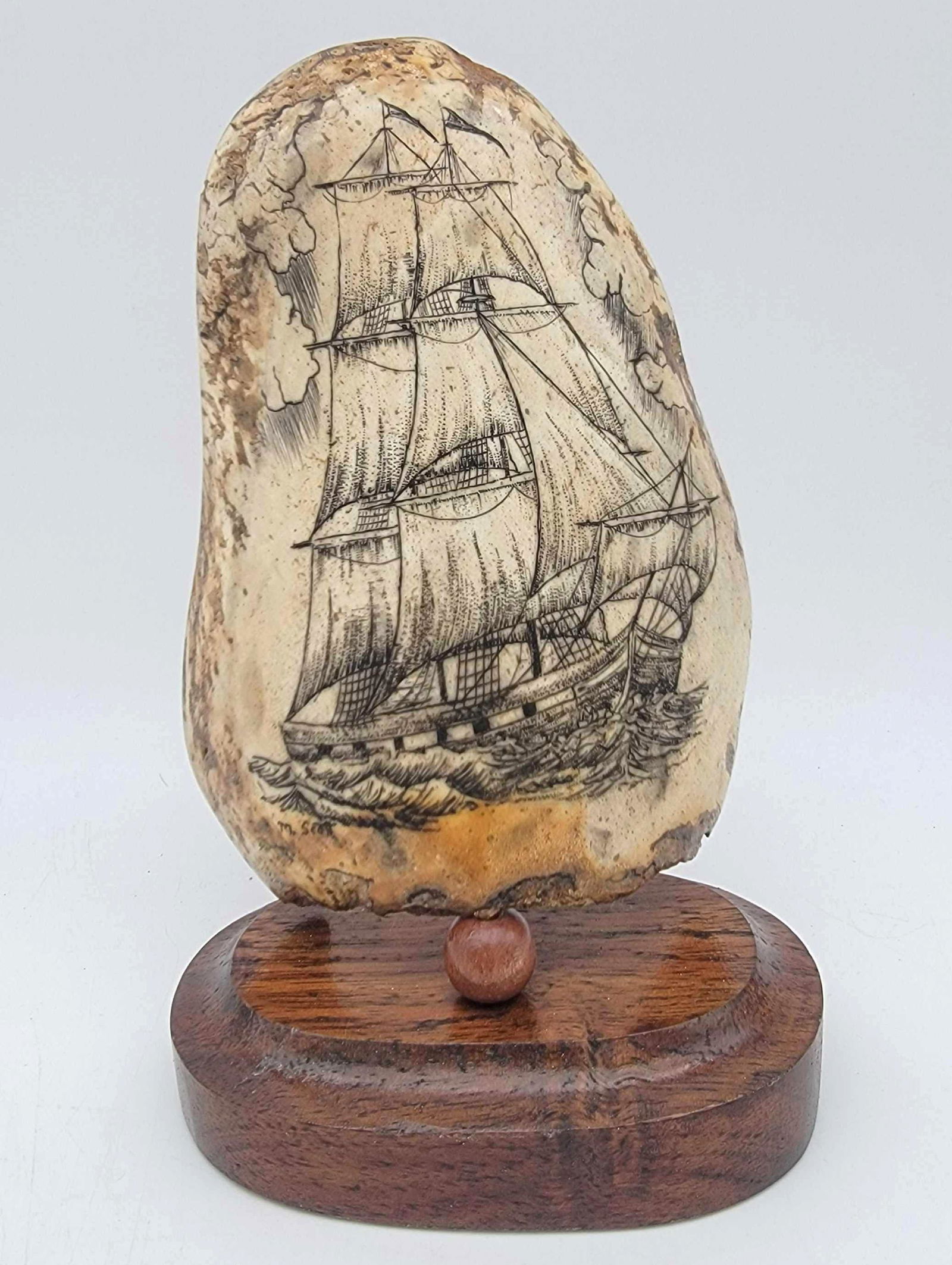 Walrus Bone w/Scrimshaw Galleon by Michael Scott: A section of Walrus skull adorned with detailed scrimshaw scene depicting a Galleon signed for Michael Scott and mounted to a wood pedestal base. Measures approximately 7.5" tall x 4.5" x 3.&#