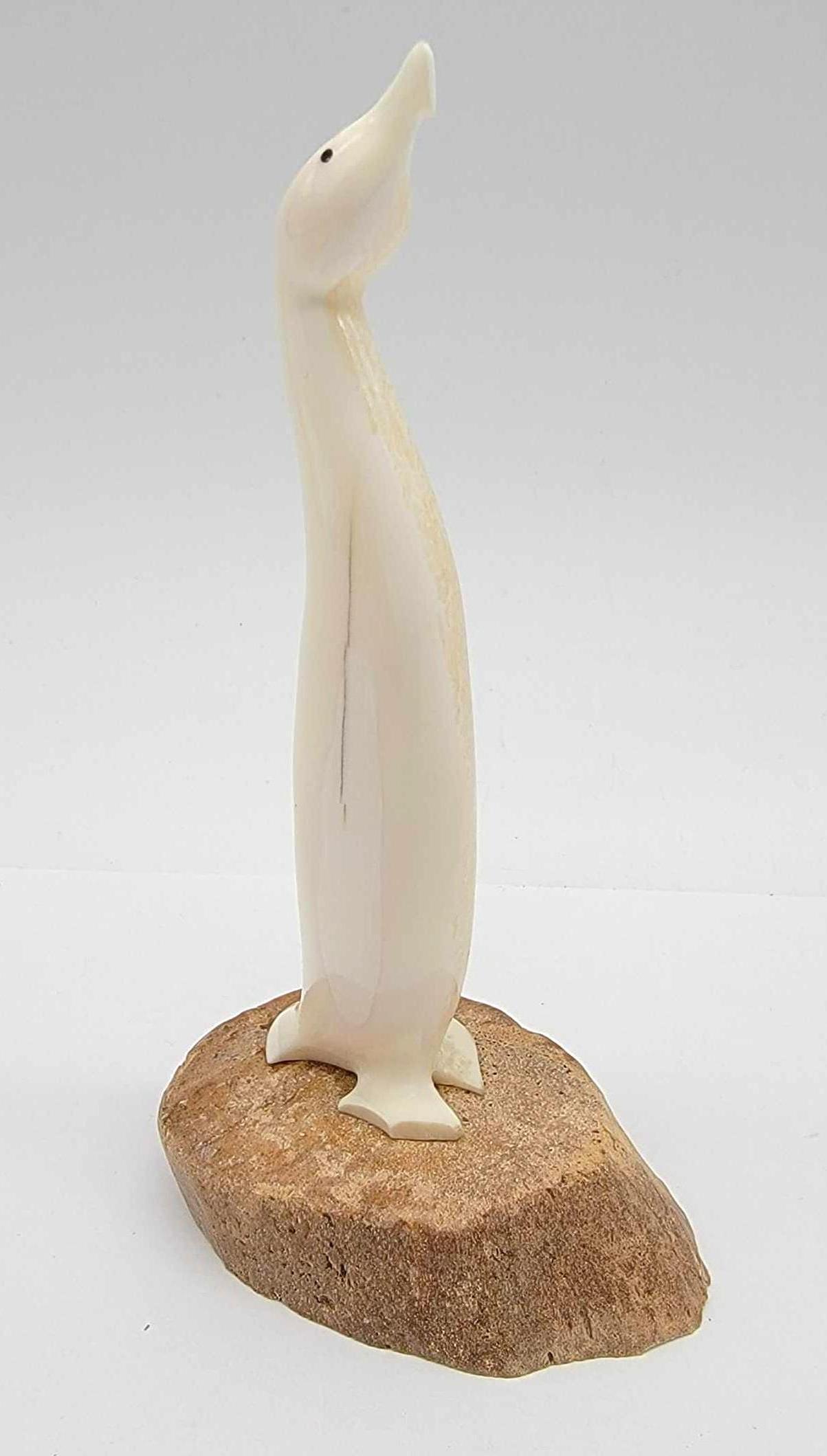5.5" Walrus Tusk Cormorant Carving by Charles Slwooko: A stylized Walrus tusk carving of a standing bird with baleen eyes, mounted on a whalebone base marked "C.S." and in excellent condition. Measures approximately 2" x 3" x 5.5" tall