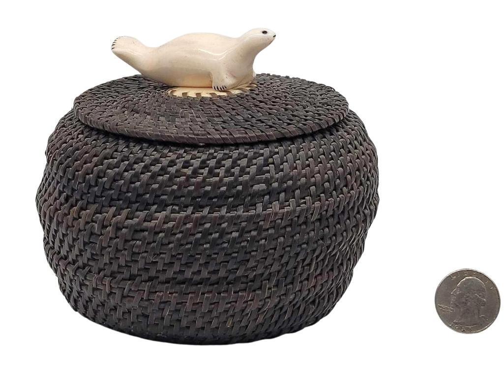 Baleen Basket with Seal Finial: A lidded baleen basket with a carved walrus tusk seal finial, signed "G.T." and dated 1975 inside. Measures approximately 5.5" in diameter x 3.25" tall without finial (4.25" tall w