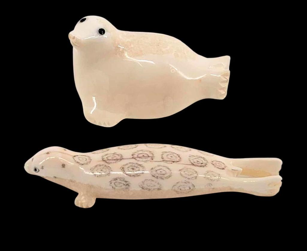 2x Eskimo Walrus Tusk Carvings of Seals: A pair of carved walrus tusk seals, one with scrimshaw features, the other with inlaid baleen eyes. The larger example measures approximately 2.5" x 1.5" x 1.25" tall.