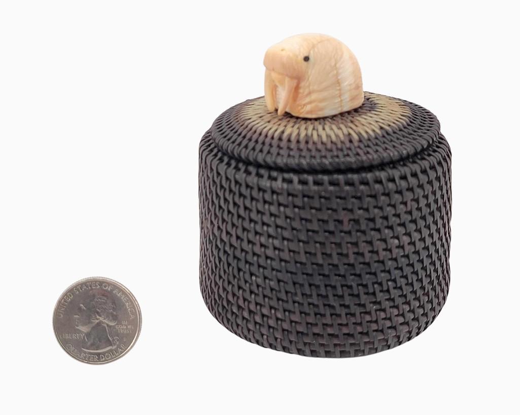 Iñupiaq Baleen Basket by Sonny Hayes: An exquisitely constructed baleen basket by the late Elim, AK Iñupiaq basket maker Sonny Hayes. The fine example features a prominent walrus finial carved from fossil walrus tusk, and contrasting