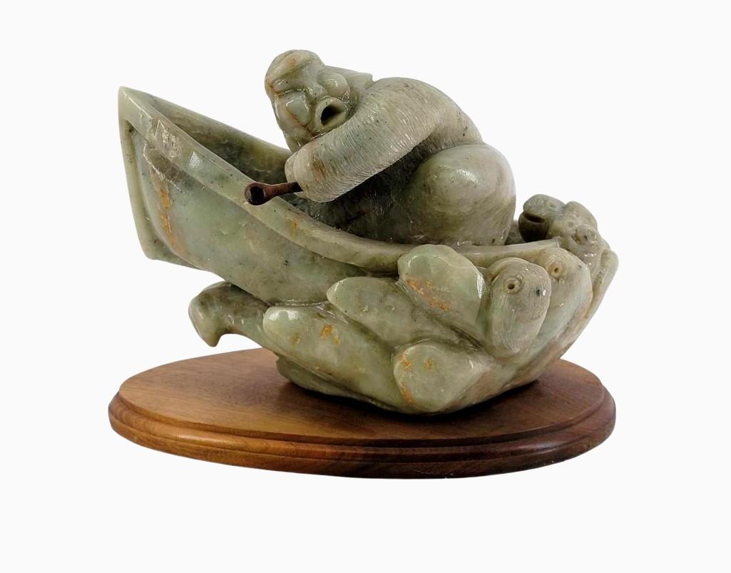 Inuit Stone Carving of Fleeing Hunter: A carved alabaster or serpentine carving depicting a concerned hunter fleeing in their vessel, the waves beneath them in the form of displeased sea creatures. No noted artist signature. Mounted a wood