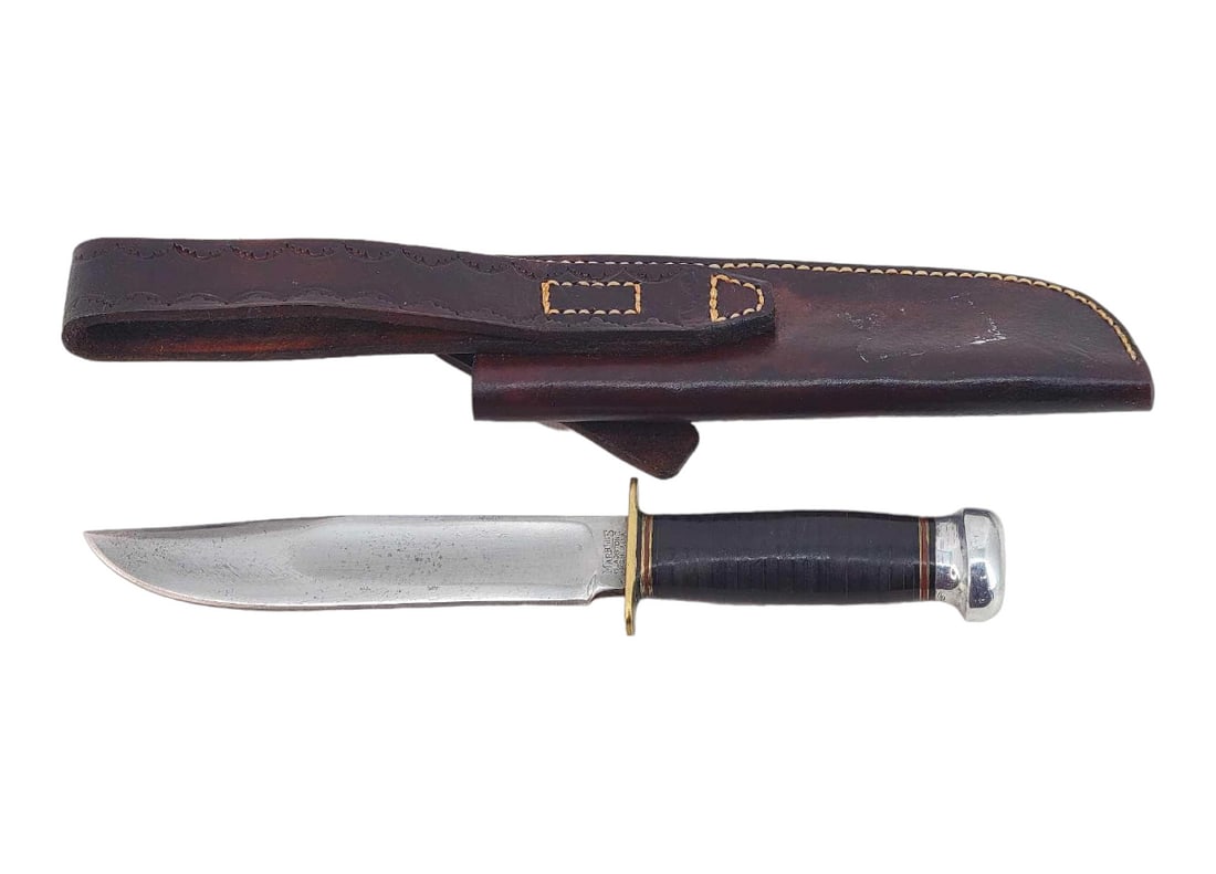 Marble's Ideal Hunting Knife - 5.5" Blade: A Marbles Ideal hunting knife with large blood groove, brass hilt, and aluminum teardrop pommel exposing a full-length rattail tang. Grip is of stacked leather and bound by spacers at either end. Hous