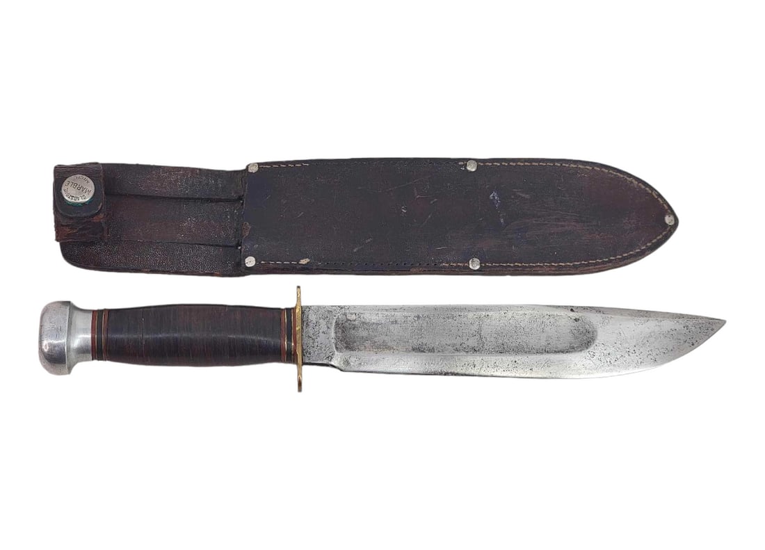 Vintage Marble's Ideal Hunting Knife w/Sheath - 7.25" Blade: A Marbles Ideal hunting knife with large blood groove, brass hilt, and aluminum pommel exposing a full-length rattail tang. Grip is of stacked leather and bound by spacers at either end. Housed in a l