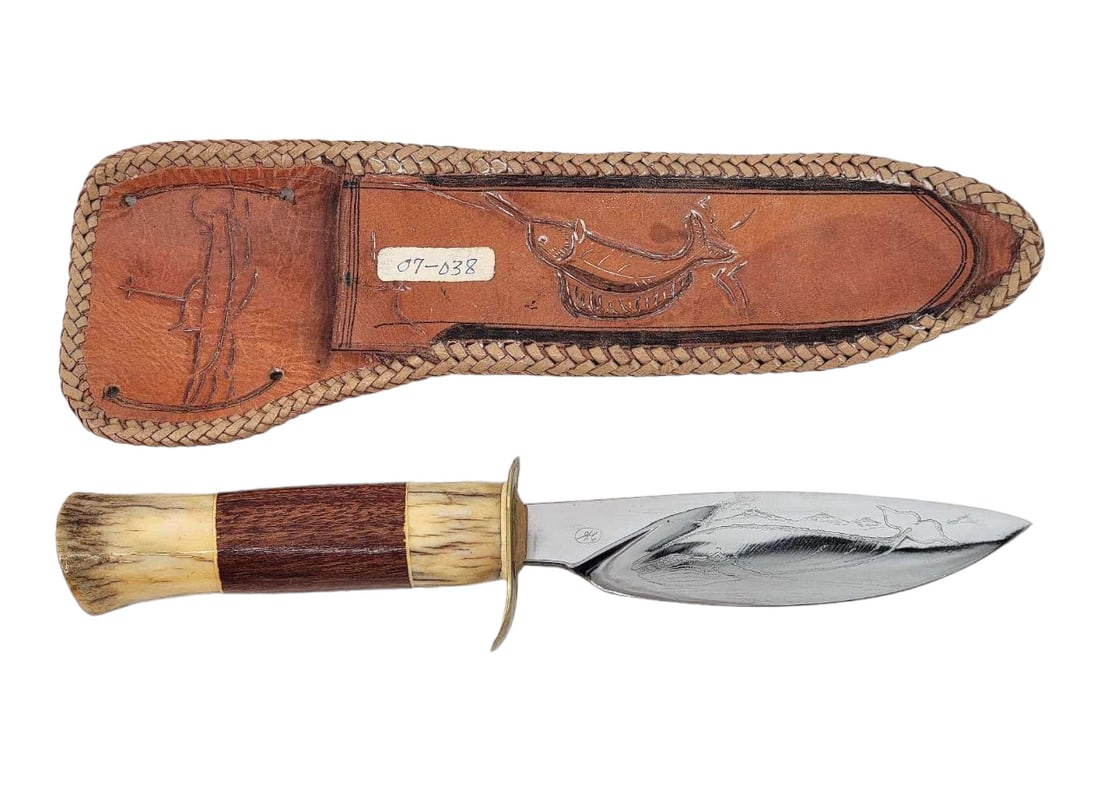 Bill Hart Nautical Engraved Knife w/ Sheath: A fixed leaf shape blade engraved with a sailing ship and fish on one side and whale on the other leading to a brass half guard and stag handle by William "Bill" Hart Jr., a self-taught skille