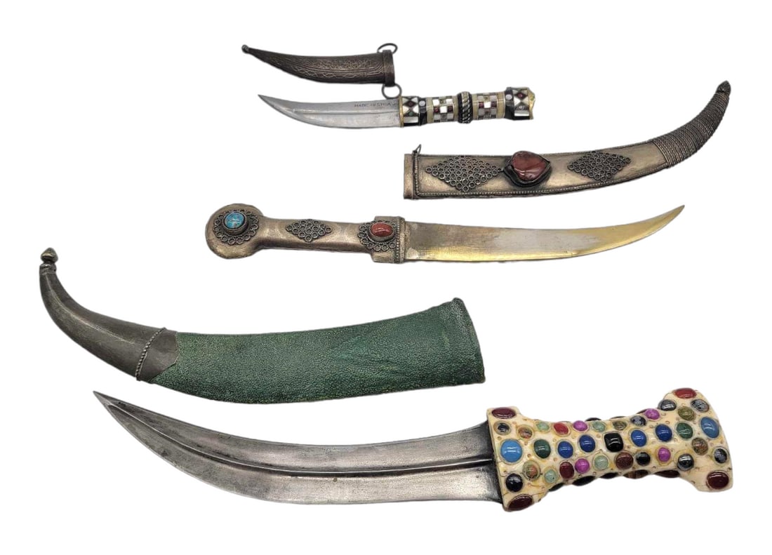Middle Eastern Fixed Blade Daggers w/ Sheaths: Three beautiful upwardly turned fixed blade daggers. Each has intricate designs only on one side, the largest featuring walrus tusk handle with set semi-precious and faux stones, jewel capped butt and