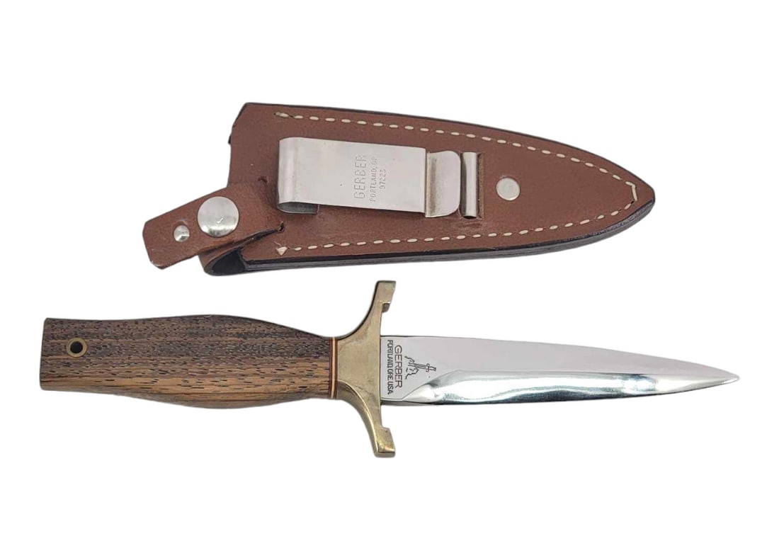 Gerber Mark I Dagger w/Sheath: A Mark I dagger c,1974-1984, marked for Gerber on the ricasso. The blade is a double edged stainless steel with mirror finish, and fully enclosed in a wooden handle with brass double guard, trio of co